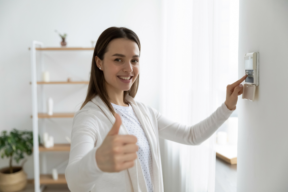 Smiling woman turning on home alarm